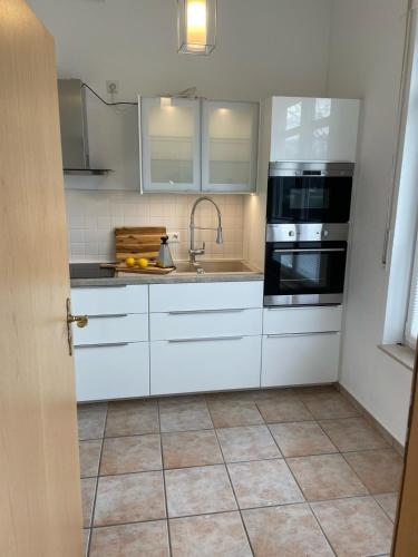 a kitchen with white cabinets and a sink at Seeliebe, 300 Meter zum Wasser, mit Terrasse und Garten in Lembruch
