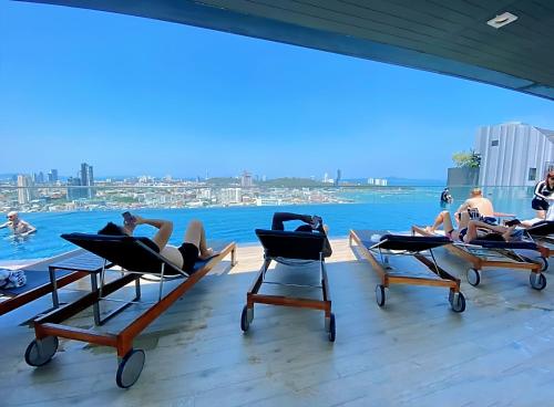 a group of people laying in lounge chairs on the roof of a building at The Base Prime in Pattaya Central