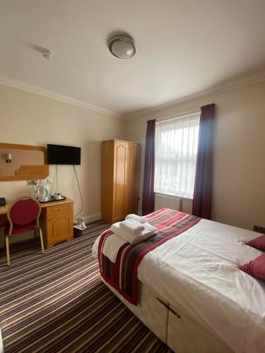 1 dormitorio con cama, escritorio y ventana en The Lawn Hotel, en Reading