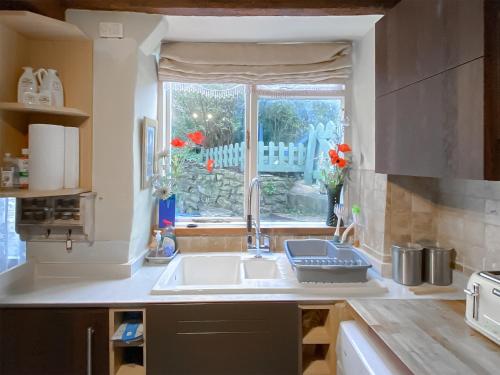 cocina con fregadero y ventana en Ashley Cottage, en Colsterworth