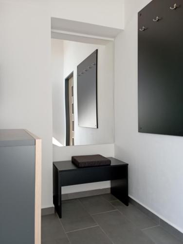 eine schwarze Bank in einem weißen Zimmer mit einem Spiegel in der Unterkunft Apartmán Nepomuk in Nepomuk