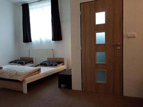 2 Betten in einem Zimmer mit Tür in der Unterkunft Apartmán Nepomuk in Nepomuk