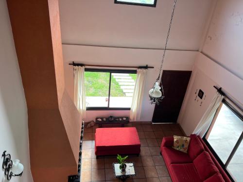 Habitación en el ático con sofá rojo y ventana en ALQUILER CASA CON PILETA EN EL MOLLAR en Salta