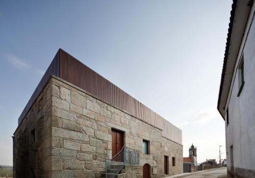 a large brick building with a fence on the side at Seven Books House in Carrazeda de Anciães