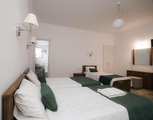 a bedroom with two beds with white and green sheets at Hotel Marybill in Perissa