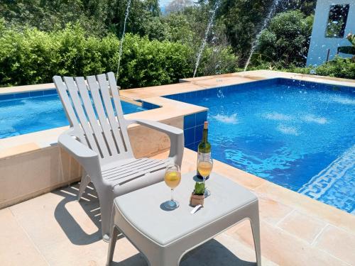two chairs and two glasses of wine next to a swimming pool at Hermosa casa de descanso en Tocaima in Tocaima