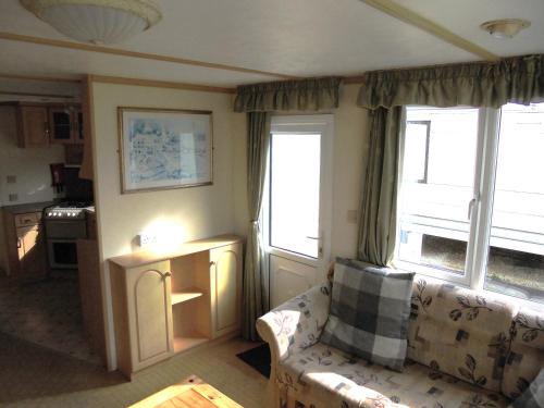 a living room with a couch and two windows at Seaview Belvedere 6 Berth Blow heated FREE WIFI in Ingoldmells