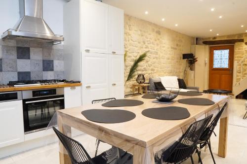 une cuisine avec une grande table et des chaises en bois dans l'établissement EXIGEHOME - Ici habita Voltaire-Maison en plein centre-ville, à Saint-Germain-en-Laye