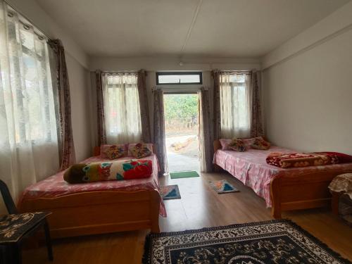 a room with two beds and a couch and a window at EVELENA Guest House in Cherrapunji
