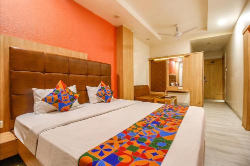 a bedroom with a large bed with an orange wall at FabHotel The Oasis - Maharana Praatap Nagar in Bhopal