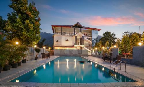 a villa with a swimming pool at night at Summit Green Lake Tea Resort & Spa in Kāziranga