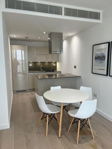 a kitchen with a table and white chairs in a room at 1 Bedroom Apartment Stratford in London