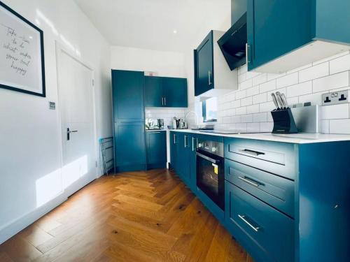 a kitchen with blue cabinets and a wooden floor at Amazing 2 Bedrooms I Brighton station I Sleep 6 in Brighton & Hove