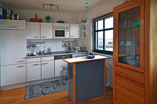 a kitchen with white cabinets and a blue island at Inselliebe in Groß Zicker