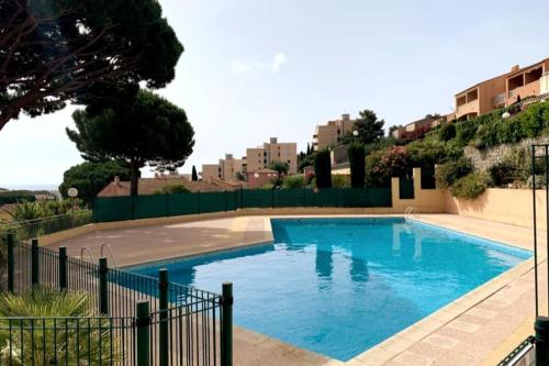 ein großer blauer Pool mit einem Zaun um ihn herum in der Unterkunft Apartment Emilia : sea view, pool and AC in Cavalaire-sur-Mer