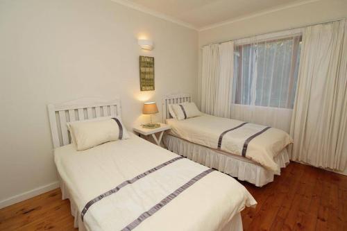 two beds in a small room with a window at Lazy Days in Natureʼs Valley