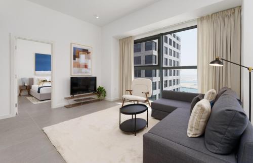a living room with a couch and a tv at Maison Privee - Modern & Panoramic Sea View Apt on Al Reem Island in Abu Dhabi