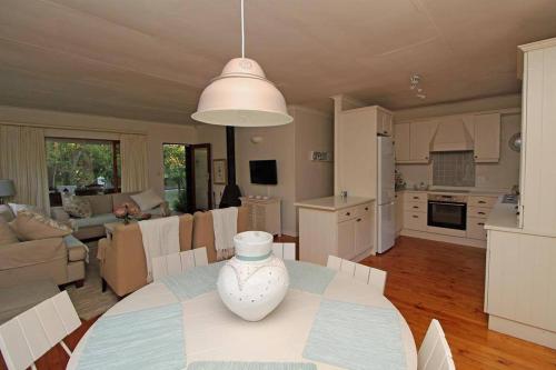 a kitchen and living room with a table with a vase on it at Lazy Days in Natureʼs Valley