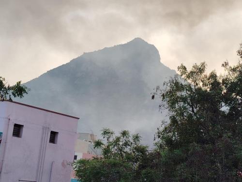 una montagna oscurata dalle nuvole con un edificio e alberi di SVM Home Stay a Tiruvannāmalai