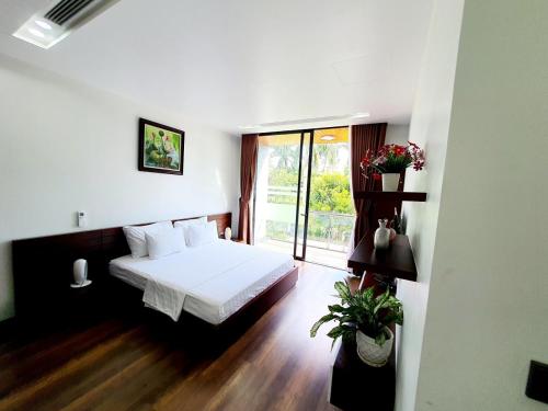 a bedroom with a bed and a large window at Flamigo Dai Lai Resort - Happy Villa in Ngọc Quang