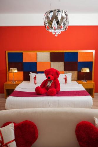 a red teddy bear sitting on top of a bed at ParkHotel by Vali Ranch Resort in Prilepnica