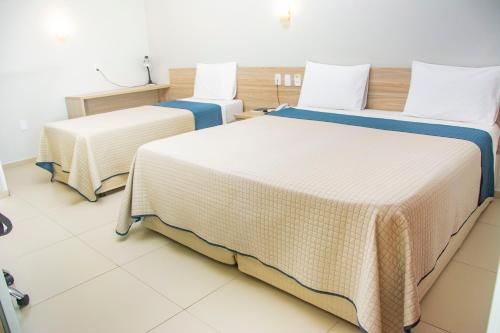 two beds in a hotel room with white walls at Citi Executivo Hotel in Parnaíba