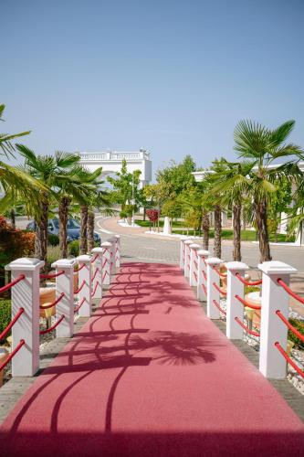 a red carpeted aisle with palm trees and a building at ParkHotel by Vali Ranch Resort in Prilepnica