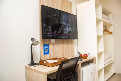a room with a desk with a television on a wall at Citi Executivo Hotel in Parnaíba