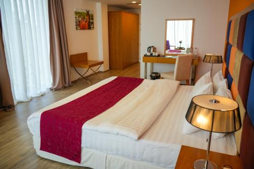 a bedroom with a large bed and a desk at ParkHotel by Vali Ranch Resort in Prilepnica