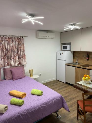 sypialnia z fioletowym łóżkiem i kuchnią w obiekcie Studio Apartment in Split w Splicie
