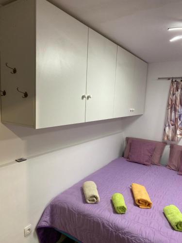 sypialnia z purpurowym łóżkiem z 2 żółtymi poduszkami w obiekcie Studio Apartment in Split w Splicie