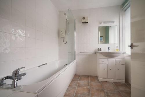 a bathroom with a tub and a sink and a shower at April Cottage in Minehead