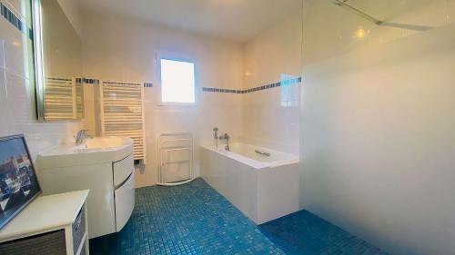 uma casa de banho branca com uma banheira e um lavatório em A proximité de la plage et du centre village, villa tout confort em Le Bois-Plage-en-Ré