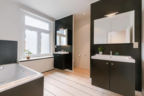 baño con bañera blanca, lavamanos y tubermott en Charming house in the city of Antwerp with parking, en Amberes