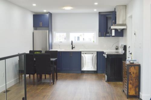 a kitchen with blue cabinets and a table with chairs at Modern East York Retreat 20 mins to DT Toronto in Toronto