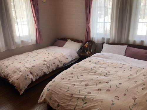 two beds sitting next to each other in a bedroom at Pension Locomotion in Kutchan