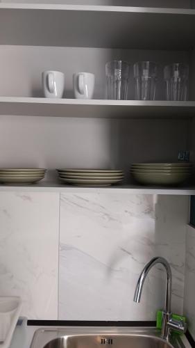 a kitchen sink with plates and cups on a shelf at B2 Urban Studio in Larisa