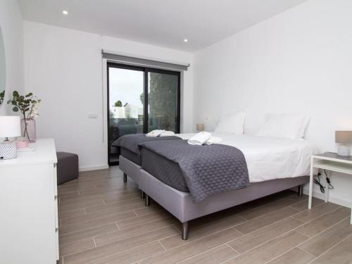 a white bedroom with a large bed and a window at Mamma Mia House by Stay ici in Pêra