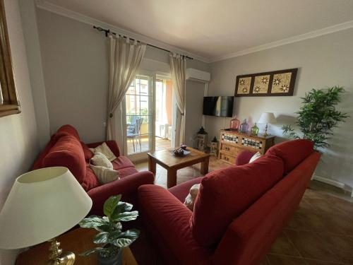 salon z 2 czerwonymi kanapami i stołem w obiekcie Apartamento Deluxe Vistas Laterales al Mar w mieście Isla Canela