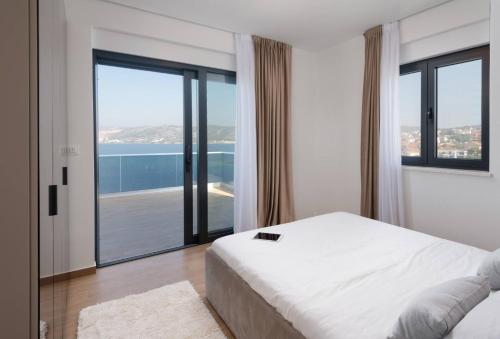a bedroom with a bed and a view of the ocean at Villa Palm Bay 1, heated pool - 5 m from the sea in Ražanj
