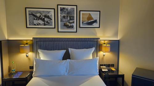 a bedroom with a bed with three pictures on the wall at Columbus Hotel Monte-Carlo, Curio Collection by Hilton in Monte Carlo