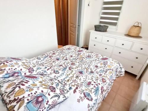 une chambre avec un lit avec un couvre-lit fleuri dans l'établissement Appartement T2 + Coin Nuit - Wi-Fi - Piscine Gratuite - Parking Privatif - À 200m Plages et Commerces - FR-1-316-282, à Six-Fours-les-Plages