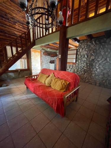 a red bed with yellow pillows on it in a room at Cabaña en los soles de montaña in Villa Pehuenia