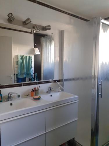 bagno bianco con lavandino e specchio di CHEZ MAMINE a Castanet-Tolosan