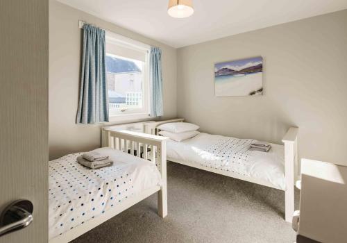 two twin beds in a room with a window at 1 North Street, Elie in Elie