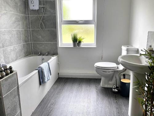 a bathroom with a tub and a toilet and a sink at Spacious 4 Bed House With Park Views in Lincolnshire