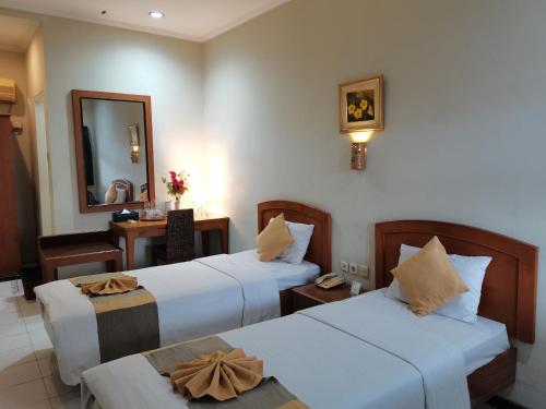 a hotel room with two beds and a mirror at Hotel Catur Putra in Magelang