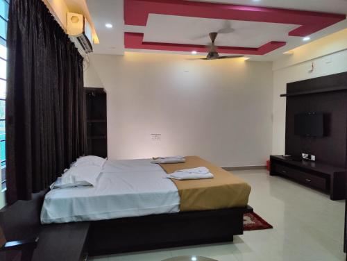 1 dormitorio con 1 cama y TV de pantalla plana en Ratna Sagar, en Udupi