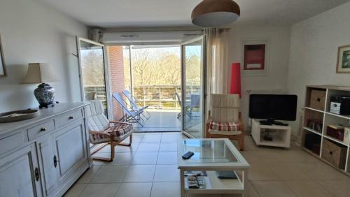 un salon avec une grande fenêtre et une télévision dans l'établissement Le Magellan Appartement Terrasse 4 personnes plage et centre ville, à Andernos-les-Bains