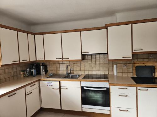 una cocina con armarios blancos y fregadero en Ferienhaus Sinning, en Leogang